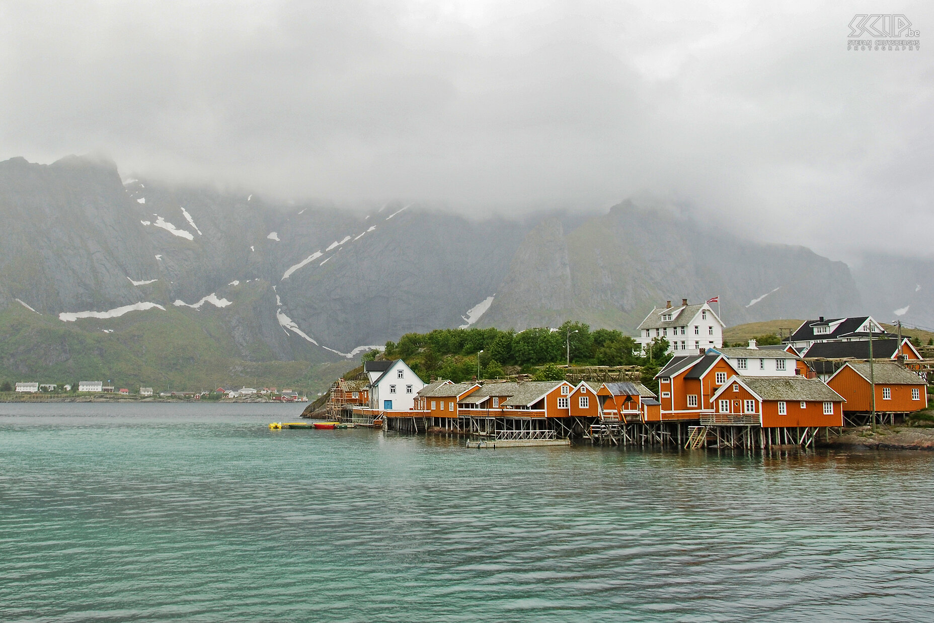 Sakrisøy in the fog After spending the night in the Munkebu hut, we descended again alongside Djupfjorden lake and via the coastal road we walked to our rorbu in Hamnøy. Along the way we passed the villages of Reine and Sakrisøy.  The orange houses of the Sakrisøy village in the mist. Stefan Cruysberghs